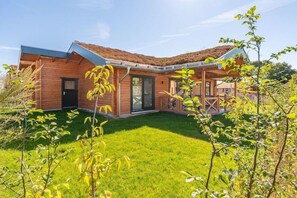 A wooden house with a sloped roof, a front porch, and a well-maintained lawn. - Ferienhaus mit eigener Sauna und schoener Terrasse (Tönning OT Kating)