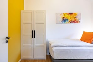 A bedroom with a bed, a wardrobe, and a colorful abstract painting on the wall. - Ferienhaus mit eigener Sauna und schoener Terrasse (Tönning OT Kating)