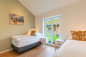 A bedroom with a bed, bedside tables, a window with a view of a garden, and a painting on the wall. - Ferienhaus mit eigener Sauna und grossem Garten (Tönning OT Kating)