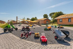 A playground with various children's vehicles and a building in the background. - Ferienhaus mit eigener Sauna und grossem Garten (Tönning OT Kating)