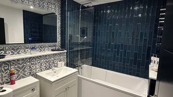 A modern bathroom with a white sink, vanity, and a freestanding bathtub.