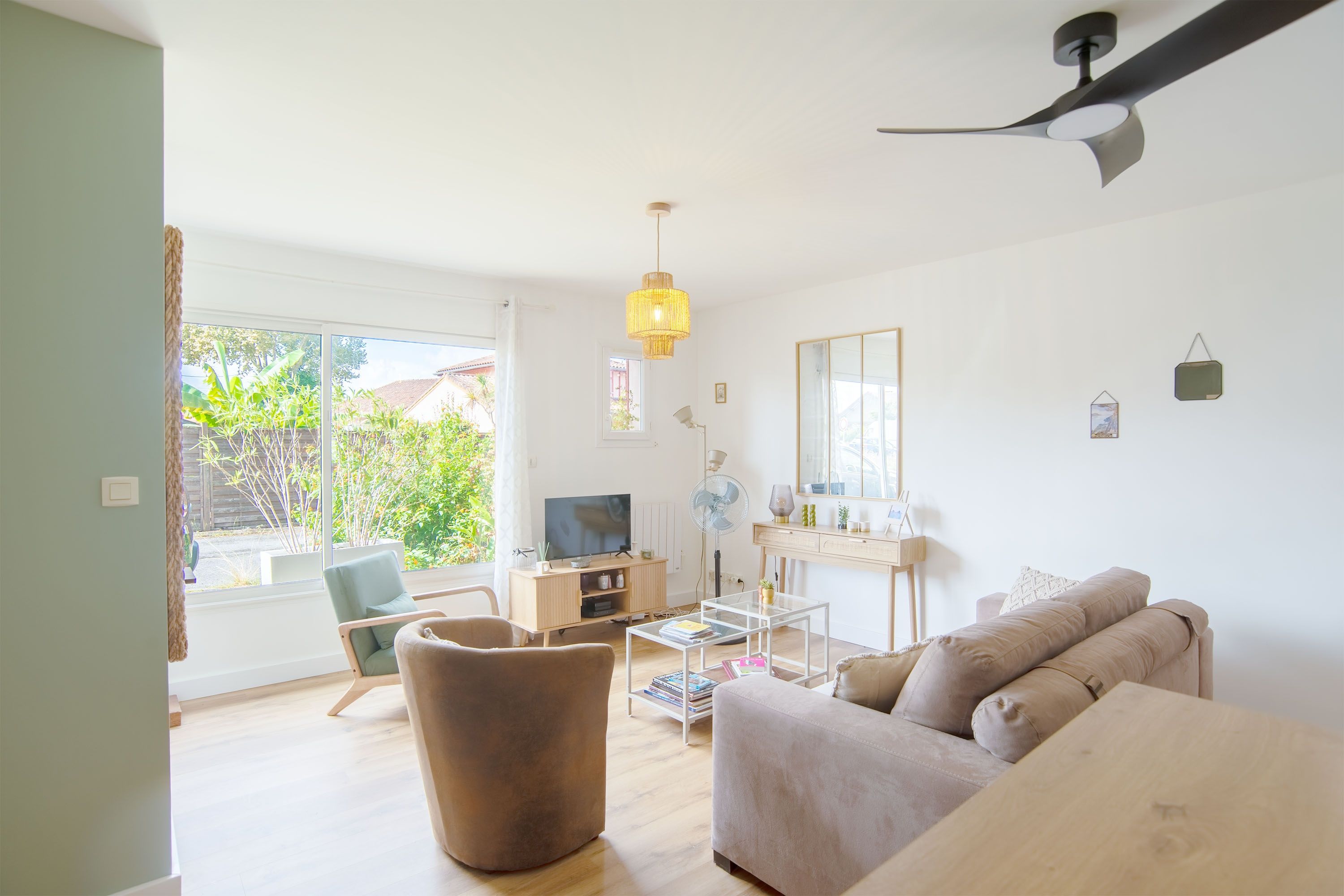A modern living room with a sofa, a chair, a coffee table, a TV, and a ceiling fan.