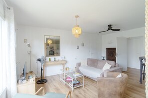 Een moderne woonkamer met een bank, een salontafel, een vloerlamp, een spiegel en een plafondventilator.