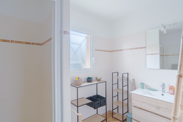 Ein Badezimmer mit Fenster, Spiegel, Waschbecken und Ablageflächen.