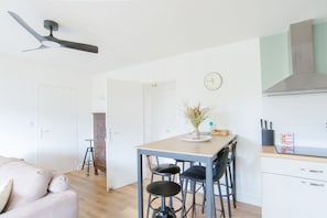 Eine moderne Küche mit Essbereich, Deckenventilator, einer Uhr und einem Barhocker.