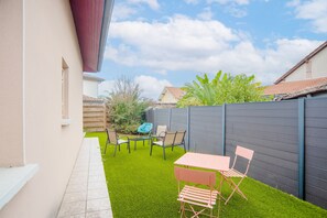 Un jardin avec un espace patio, une table et des chaises.