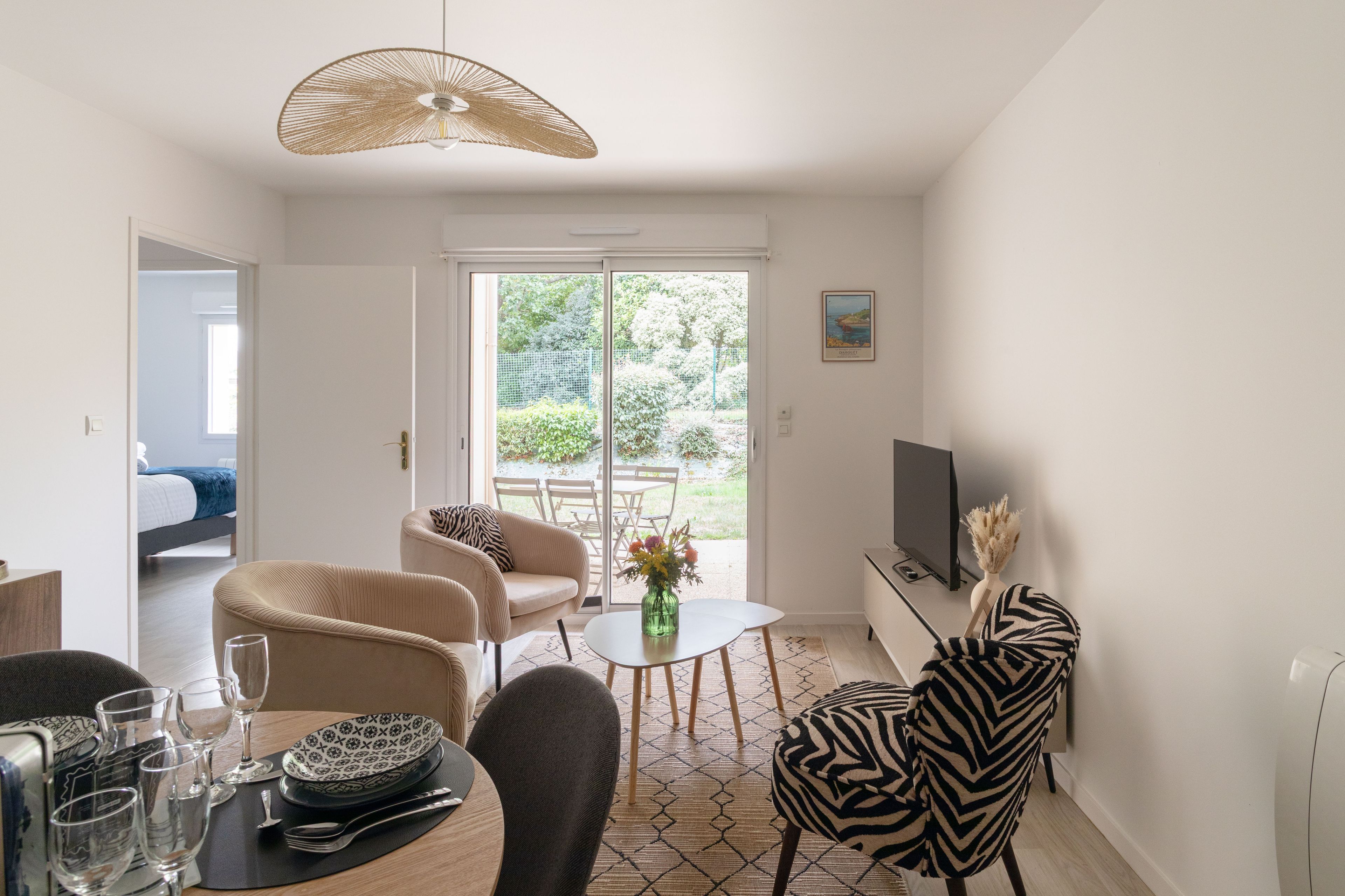 Un salon moderne comprenant un canapé, des fauteuils, une table à manger et un téléviseur.