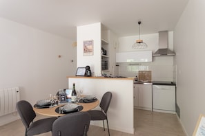 A modern kitchen with a central island, white cabinetry, and a hanging light fixture. - Pic épeiche - proche de la plage (Pléneuf-Val-André)