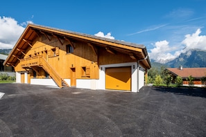 A wooden chalet with a garage and a staircase leading to a balcony. - Chalet Soline La Glière - Appartement avec jardin (Samoëns)