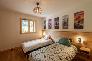 Une chambre avec deux lits, une fenêtre et des œuvres d’art murales.