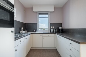 A compact kitchen with a window, a stove, and a coffee maker. - L'échappée Vannetaise - T2 avec parking privé (Vannes)