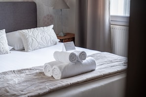 A neatly made bed with rolled white towels and a sign on the bed. - L'échappée Vannetaise - T2 avec parking privé (Vannes)