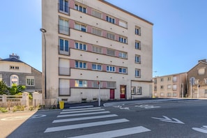 En flervåningsbyggnad med bostäder, en slät fasad, en röd dörr och ett övergångsställe framför.