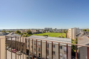 Ett bostadsområde med utsikt över en grön sportplan, byggnader och parkerade bilar.