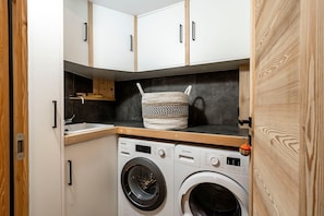 A compact laundry room with a washing machine, a drying rack, and a woven basket on the countertop. - Chalet Casacamo - Chalet au pied des pistes (La Salle-les-Alpes)