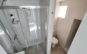 Ein modernes Badezimmer mit einer Duschkabine, einer Toilette und einem Waschbecken.
