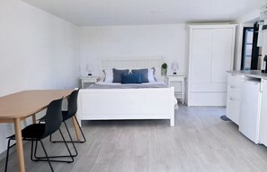 Ein Schlafzimmer mit einem Bett, Nachttischen, einem Schreibtisch mit Stühlen und einem Kleiderschrank.