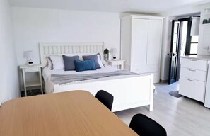 Ein modernes Schlafzimmer mit Bett, Nachttischen, einem Kleiderschrank und einem Essbereich.