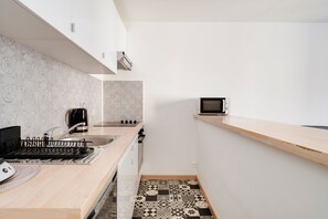 Een kleine keuken met een magnetron, kookplaat en koffiezetapparaat.