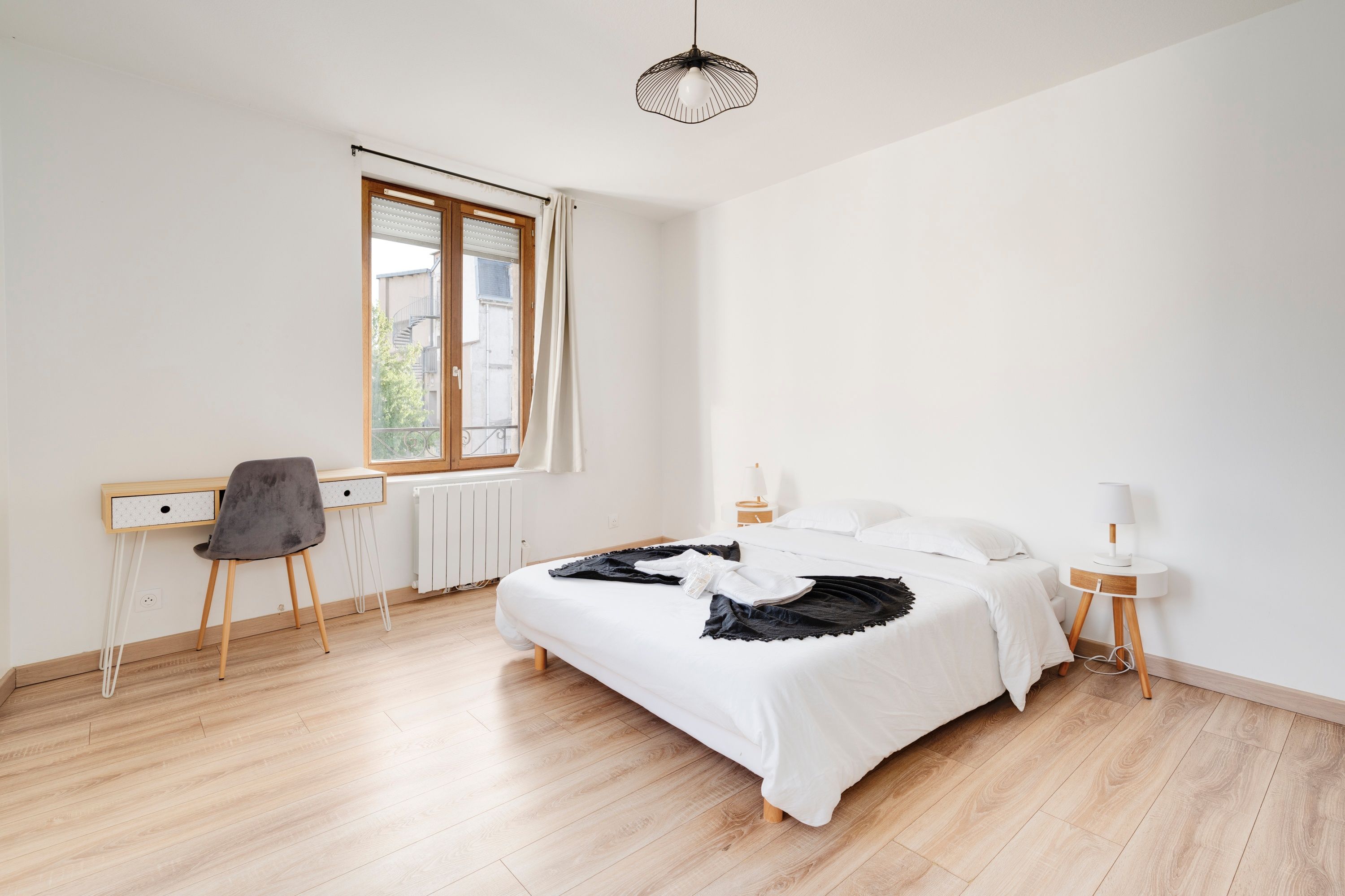 Une chambre à coucher au style minimaliste, avec un grand lit, un bureau et une chaise.