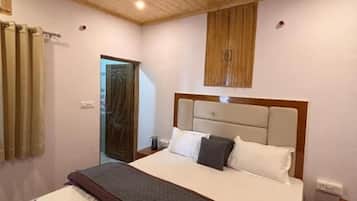 Un dormitorio con techo de madera, una cama con cabecera, una mesita de noche y una ventana con cortinas.