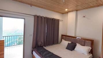 A bedroom with a wooden ceiling, a large bed, a window with curtains, and a balcony.