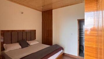 A bedroom with a wooden ceiling, a bed with a headboard, and a wooden floor.