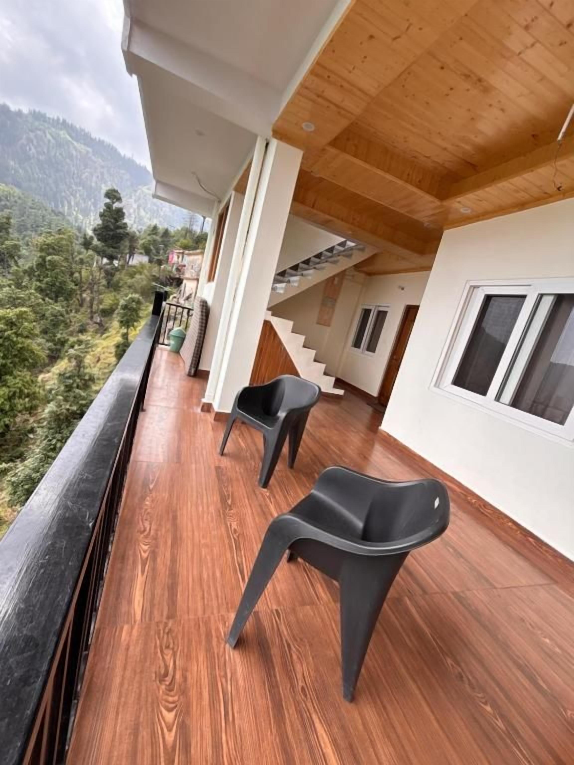 A wooden deck with two chairs, a staircase, and a view of a mountainous landscape.