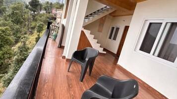 A wooden deck with two chairs, a staircase, and a view of a mountainous landscape.