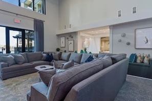 A modern living room with a sectional sofa, a coffee table, and a dining area in the background. - Modern Midtown, Minutes to Broadway, Parking, Pool (Nashville)