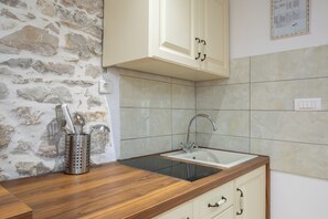 A kitchen with a stone wall, wooden countertop, and a sink with a faucet. - B - luxury spacious studio with terrace in the heart of Split (Split)
