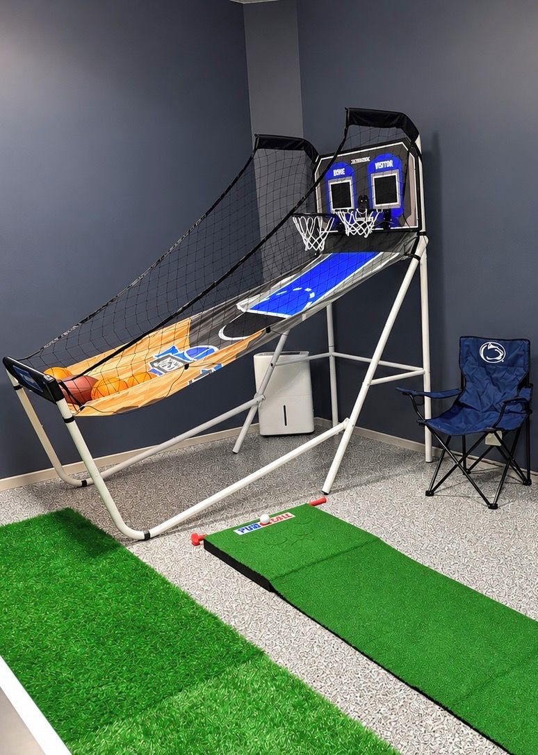 A basketball hoop with a net, a blue chair, and artificial grass flooring.