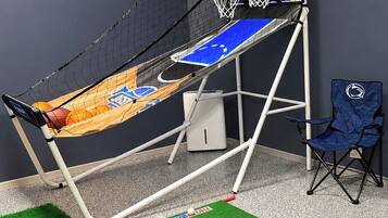 A basketball hoop with a net, a blue chair, and artificial grass flooring.