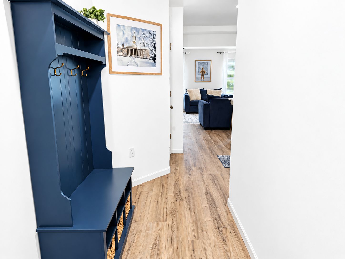 A modern living room with a dark blue bench, a framed picture on the wall, and a wooden floor.