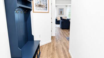 A modern living room with a dark blue bench, a framed picture on the wall, and a wooden floor.