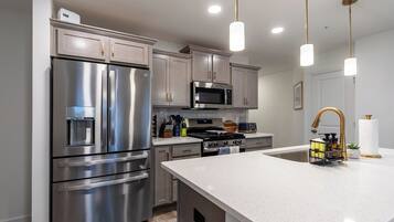 A modern kitchen with stainless steel appliances, a central island, and pendant lighting.