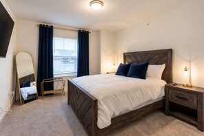 A neatly arranged bedroom with a large bed, bedside lamps, a bedside table, a mirror, and a window with curtains. - 2 Back-to-Back Homes | Sleeps 18 | Near PSU (Bellefonte)