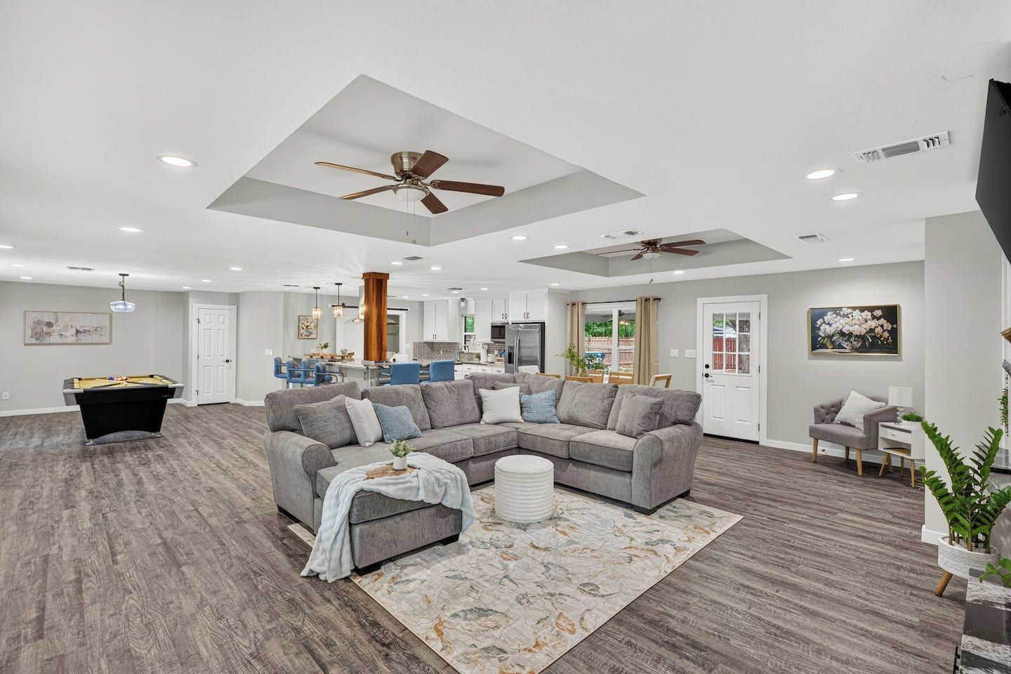 A spacious living room with a sectional sofa, a pool table, and ceiling fans.