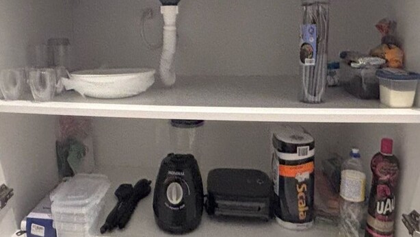 Une étagère contenant divers objets, notamment une bouteille d’eau, un récipient et une boîte de conserve.