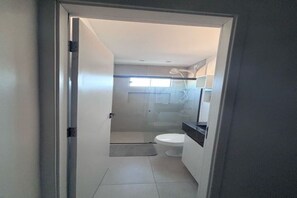 Casa de banho com sanita, chuveiro e lavatório.