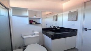 Une salle de bain moderne équipée de toilettes, d’un lavabo, d’un miroir et d’un porte-serviettes.