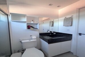 Uma casa de banho moderna com sanita, lavatório, espelho e porta-toalhas.