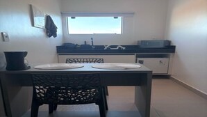 Une cuisine de taille réduite comprenant une table à manger, des chaises, une fenêtre et un four à micro-ondes.