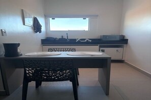 Uma cozinha compacta com mesa, cadeiras, janela e micro-ondas.