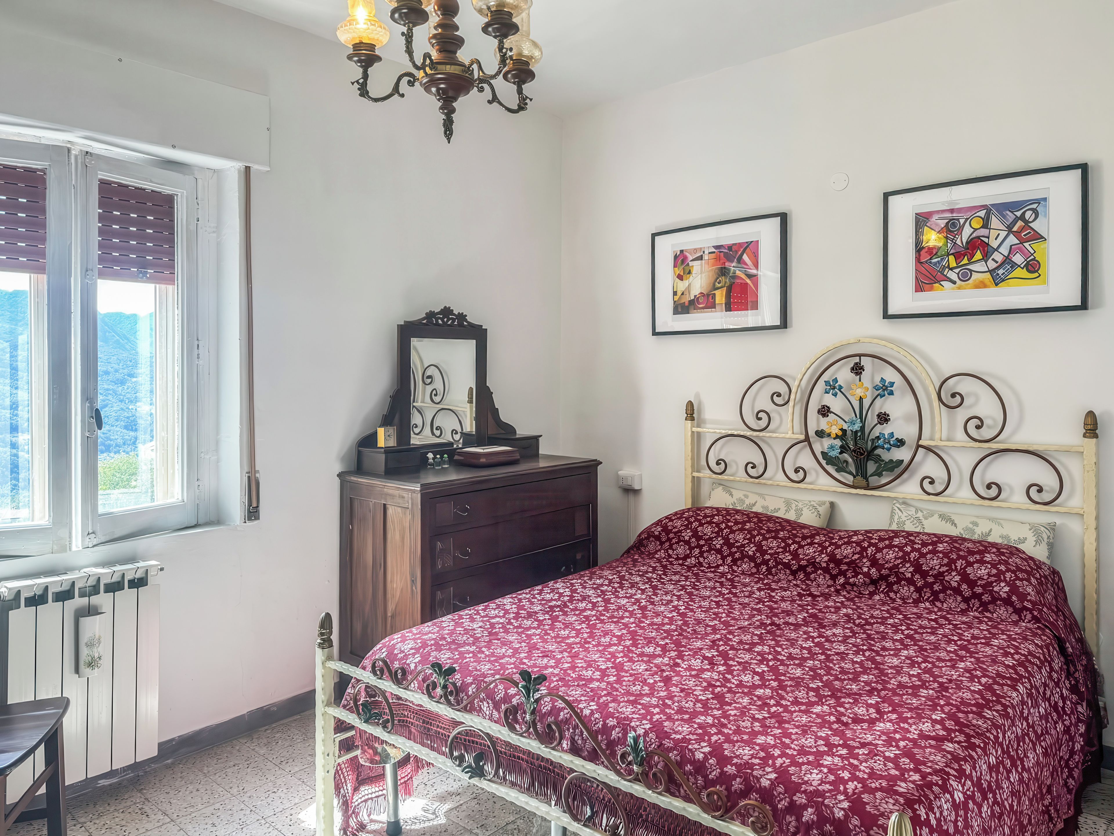 A bedroom with a bed, dresser, and two framed artworks on the wall.