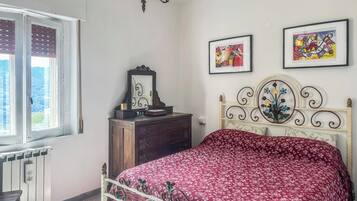 A bedroom with a bed, dresser, and two framed artworks on the wall.
