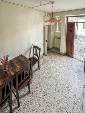 A dining area with a wooden table and chairs, a hanging light fixture, and a view of the outside.
