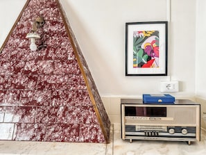 A room with a marble-patterned wall, a framed abstract painting, and a vintage radio.