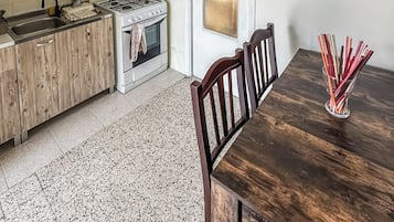 A kitchen with a wooden cabinet, a stove, and a dining table with chairs.