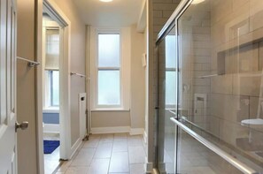 A bathroom with a glass shower enclosure, a white bathtub, and a window providing natural light. - Minutes to Capitol & UPMC  Monthly w/ Parking. Perfect for Professionals; 2nd Fl (Harrisburg)